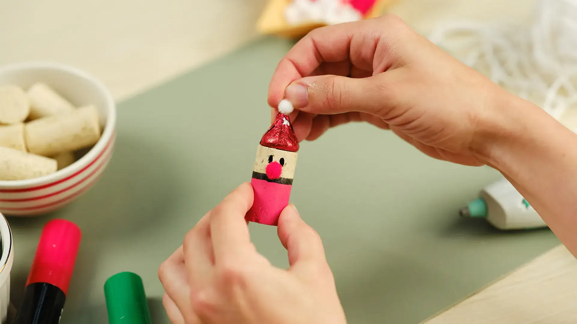 A white pom pom being applied to the top of a hat