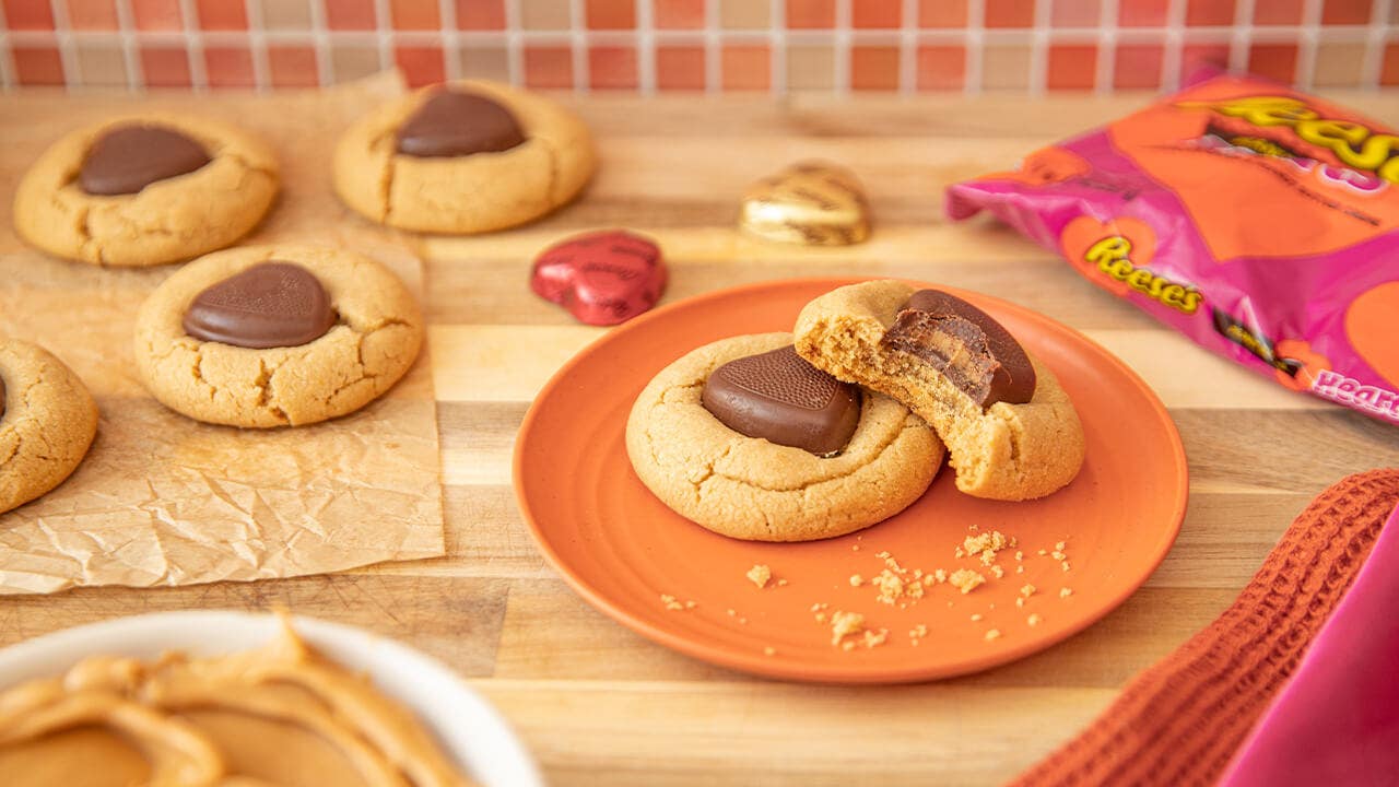 freshly baked reeses heart cookies, one with a bite taken from it